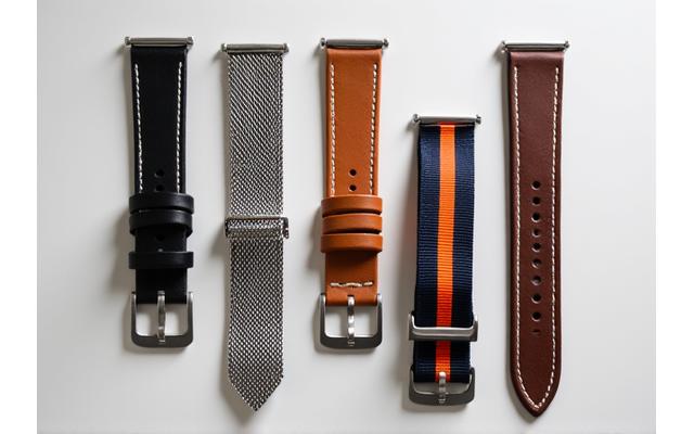 A collection of various watch straps including leather, metal, and NATO styles, neatly arranged.